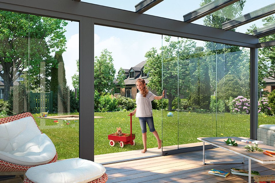 Espace de vie extérieur avec une structure en verre, un jardin verdoyant, et une femme avec un jouet rouge. Espace de vie extérieur avec une structure en verre, un jardin verdoyant, et une femme avec un jouet rouge.