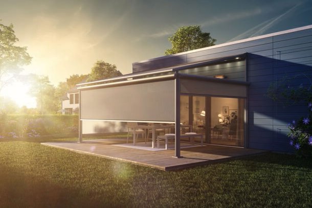 Un jardin avec une terrasse, un auvent discret et un éclairage doré du coucher de soleil.