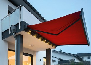 Markise in rot und schwarzem Rahmen über einem Balkon, mit integrierten LED-Spots. 