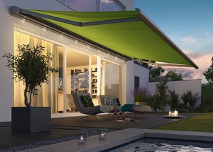 Markise in leuchtendem Grün über einer Terrassensituation mit stimmungsvollem Licht und modernen Möbeln. 