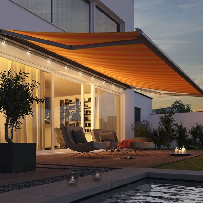 Markise in Orange über einer Terrasse mit modernen Möbeln, umgeben von Pflanzen und einem Pool.