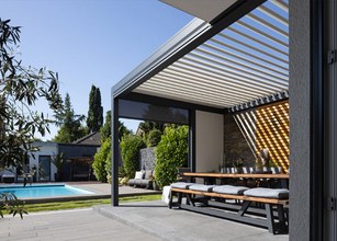 Moderne Überdachung mit Markisenkasten, großer Terrassensituation und Pool im Hintergrund. 
