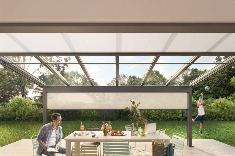 Intérieur de véranda avec table, chaises et verre, vue sur un jardin verdoyant. Intérieur de véranda avec table, chaises et verre, vue sur un jardin verdoyant.