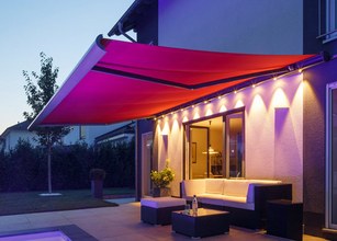 Markise in Rot über einer Terrassensituation bei Dämmerung, beleuchtet von LEDs. 