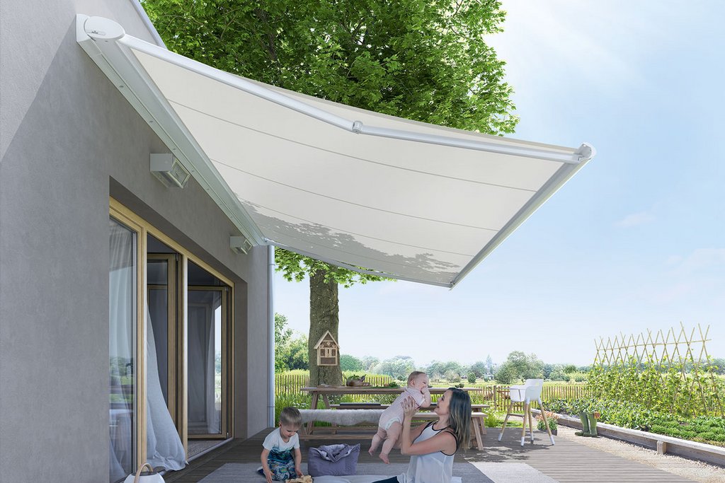 Image d'une terrasse avec une surplomb blanc, des personnes assises et un jardin en arrière-plan.