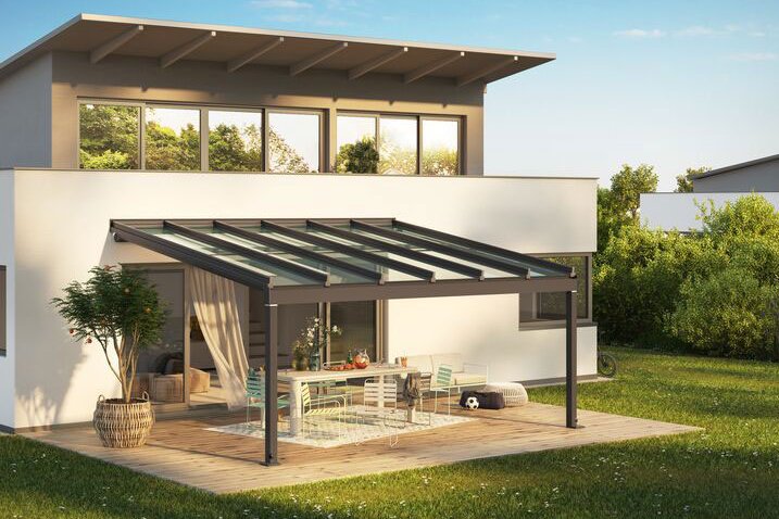Maison moderne avec une terrasse, une structure de verre et un espace de vie extérieur, entourée de verdure. Maison moderne avec une terrasse, une structure de verre et un espace de vie extérieur, entourée de verdure.