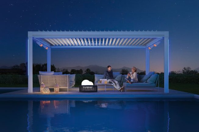 Ensemble de terrasse avec une surélévation, éclairage et des personnes assises près d'une piscine sous un ciel étoilé.