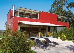 Moderne Architektur mit roter Fassade, Markise, Überdachung und Terrassensituation. 