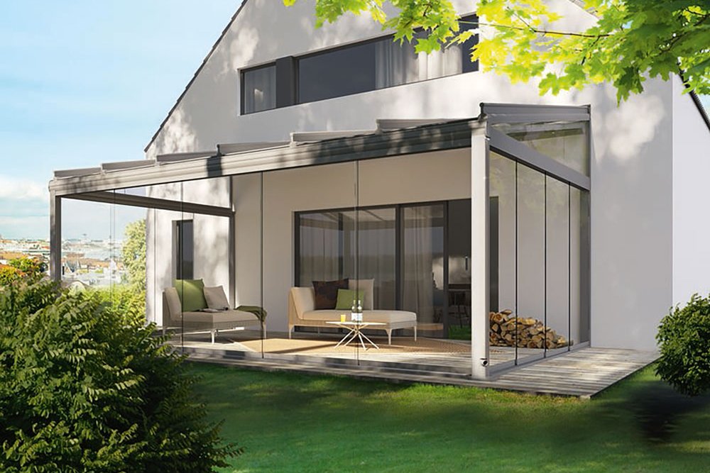 Moderne Fassade mit Glas-Schiebewänden, Überdachung und Terrasse in grüner Umgebung. Moderne Fassade mit Glas-Schiebewänden, Überdachung und Terrasse in grüner Umgebung.