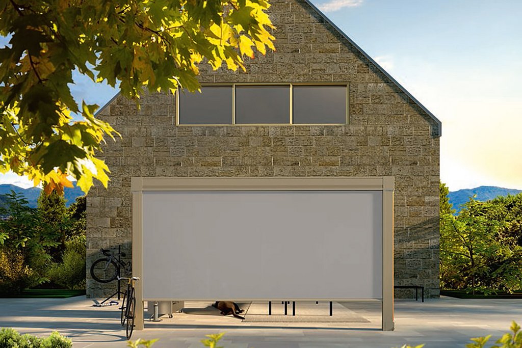 Maison en pierre avec une terrasse, équipée d'une couverture et entourée de verdure.