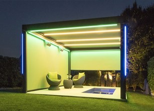 Moderne Überdachung mit zwei gemütlichen Sitzgelegenheiten und indirekter Beleuchtung in grün und blau. 