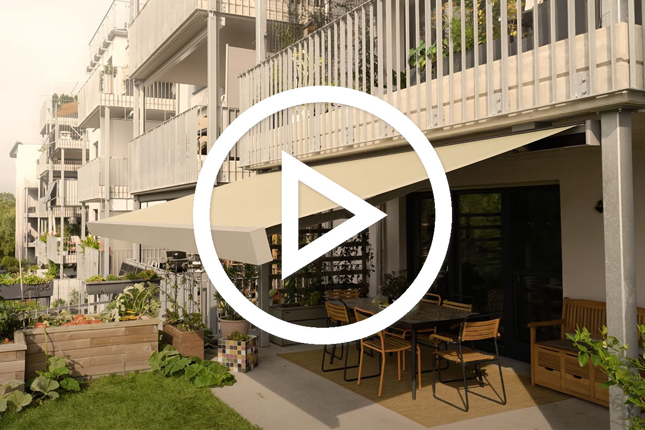 Eine Markise in hellem Farbton über einem Tisch mit Stühlen in einer Terrassensituation.