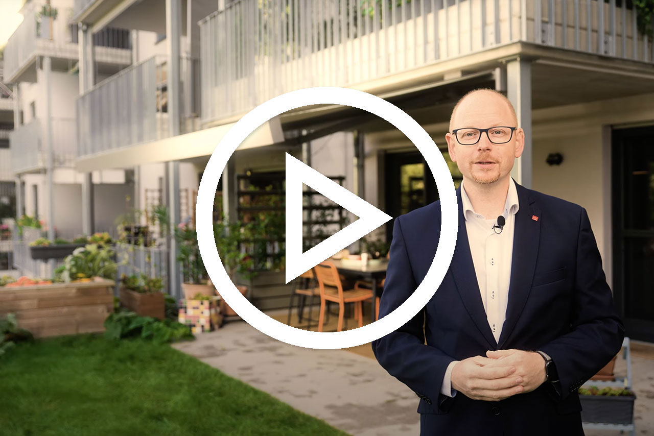 Mann in Anzug vor modernem Gebäude mit Terrasse und Grünflächen, Spielsymbol in der Mitte.