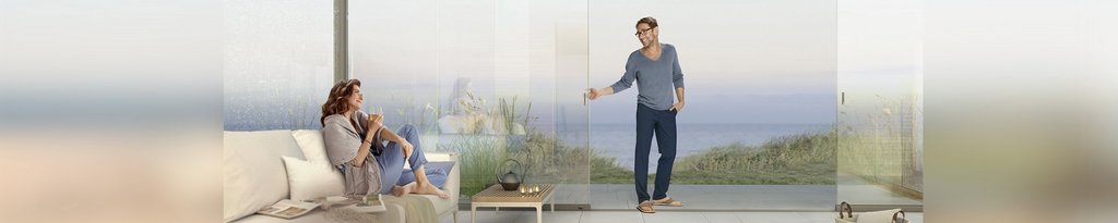 Twee mensen in een moderne omgeving met glazen schuifwanden en uitzicht op zee. Twee mensen in een moderne omgeving met glazen schuifwanden en uitzicht op zee.