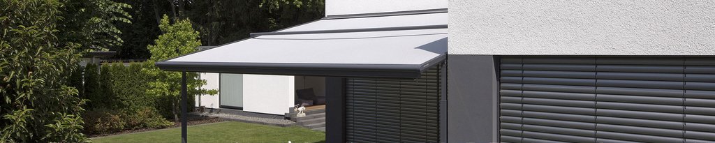 A grey awning extending from a building, with greenery in the background. A grey awning extending from a building, with greenery in the background.