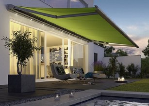 A vibrant green awning provides shade over a modern terrace setting with seating and greenery. 