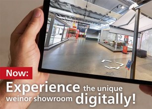 A person holding a tablet displaying a digital showroom with a modern interior layout. 