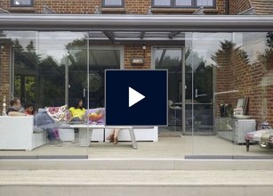Glass enclosure with a modern design, featuring seating and a view of the outdoors. 