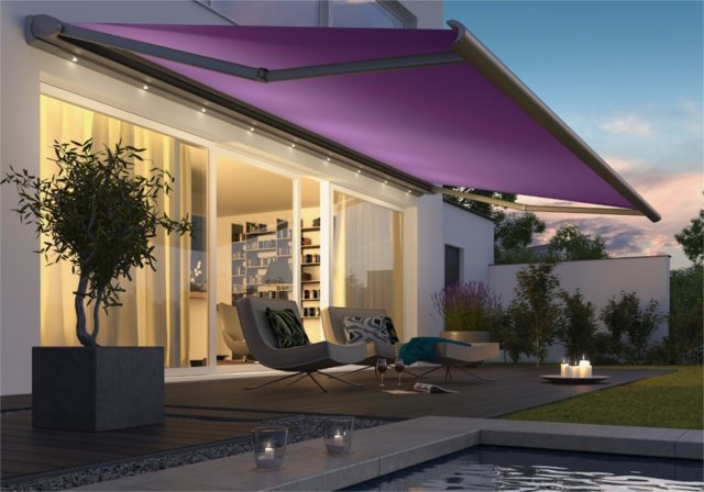 A purple awning extends over a terrace with modern furniture and a relaxing atmosphere in the evening light. A purple awning extends over a terrace with modern furniture and a relaxing atmosphere in the evening light.