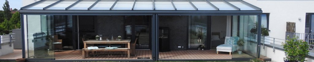 Ein moderner Wintergarten mit Glas-Schiebewänden und einem Holzterrassenboden.