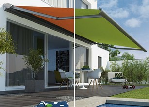 Markise in zwei Farben, orange und grün, über einer Terrassensituation mit Möbeln und Pflanzen. 