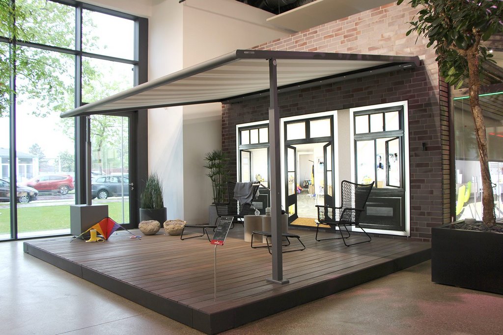 Terrasse avec une structure de toit en toile, entourée de fenêtres et de verdure. Terrasse avec une structure de toit en toile, entourée de fenêtres et de verdure.
