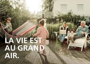 Scène de jardin avec un hamac, un enfant jouant et des adultes assis, ambiance ensoleillée et détendue. 