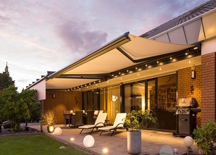 Terrassensituation mit Markise, Überdachung und Beleuchtung in einem warmen, einladenden Ambiente. 