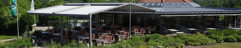 Eine Terrasse mit Markisen und Überdachung, umgeben von Pflanzen und einem Gebäude im Hintergrund.