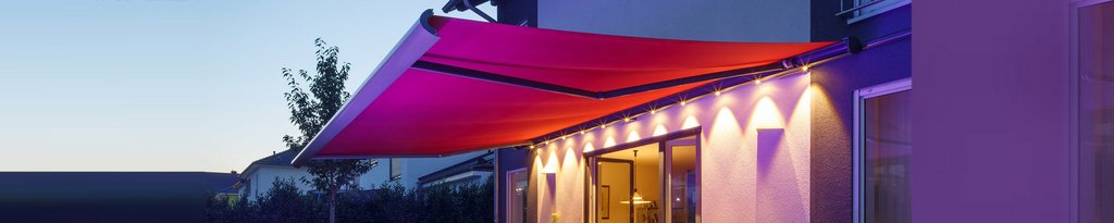 A vibrant red awning extending over a terrace, illuminated by soft lights in the evening. A vibrant red awning extending over a terrace, illuminated by soft lights in the evening.