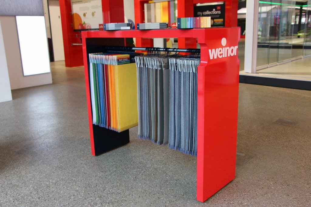 Bureau rouge avec échantillons de couleurs suspendus en dessous, à l'intérieur d'un espace moderne. Bureau rouge avec échantillons de couleurs suspendus en dessous, à l'intérieur d'un espace moderne.